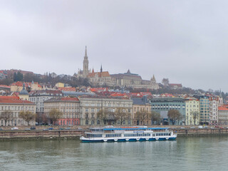 Obraz premium View of Buda and Pest district and boats from Szechenyi bridge, the chain bridge connecting Buda and pest over the Danube river, Budapest, Hungary 