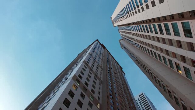 Bottom-up view of tall skyscrapers with blue sky in the background.