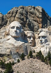 Fototapeta premium Colossal carving of four distinct faces sculpted into the side of a large, rugged mountain under a clear blue sky ,profile ,landmark ,overview