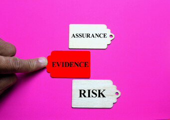 Fototapeta premium Wooden tags on pink background with assurance evidence and risk words symbolizing business decision making compliance and accountability for editorial and educational stock photo use