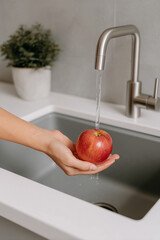 Washing a Fresh Red Apple Under Running Water in a Modern Kitchen Sink