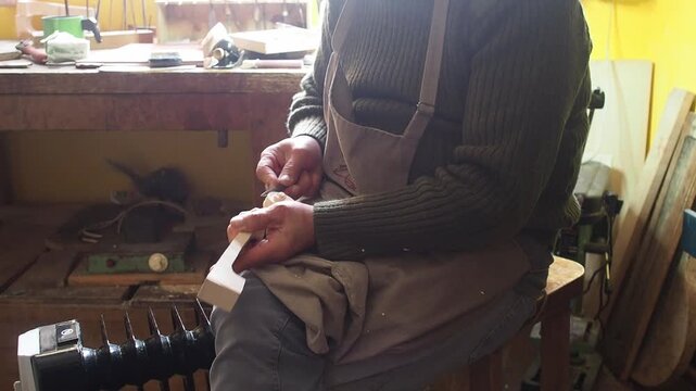 Violin maker meticulously carving a new violin scroll in a rustic workshop