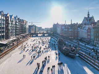 Obraz premium Hundreds of people walk along the frozen Motława River in Gdańsk during a frosty winter. Poland