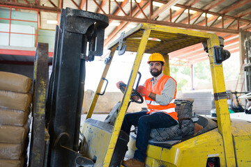 Warehouse worker man driving forklift in industrial building, moving construction materials and...