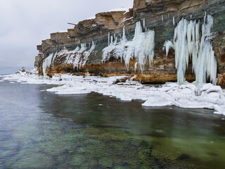 Aerial drone view of magnificent frozen waterfalls and giant icicles on the limestone cliffs of Paldiski over the Baltic Sea