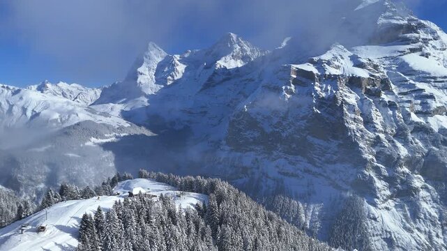 Drone video of M&auml;nnlichen in winter, featuring snow-covered ski slopes, alpine terrain, and scenic mountain views in Switzerland.