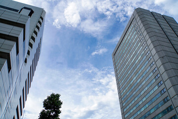 モダンな高層ビルに狭間から見上げる雲がかった青空