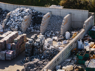 An aerial view of a metal recycling plant showing piles of scrap metal ready for sorting and...