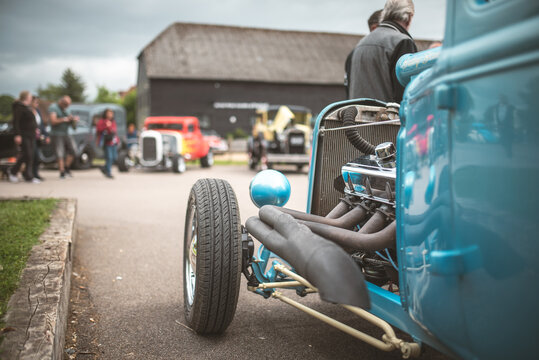 Classic blue hot rod with exposed engine and chrome details at a car show