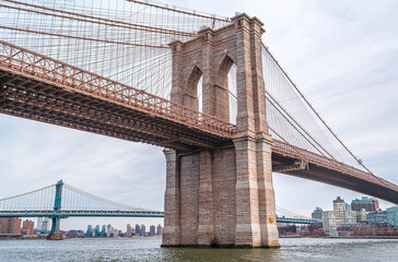 Obraz premium The scenic views of the Brooklyn Bridge, which is a cable-stayed suspension bridge in New York City, spanning the East River between the boroughs of Manhattan and Brooklyn.
