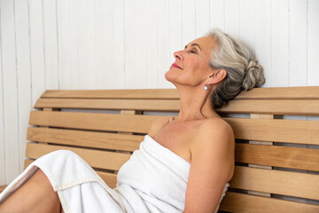 Photo of a woman relaxing in a wooden steam sauna. Rejuvenation. Healthy habits. Improved blood circulation.