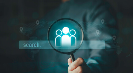 Fototapeta premium Global recruitment and talent search concept. Magnifying glass focusing on group icon with digital search bar and world map background. International market research and human resources hunting.