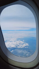 Fototapeta premium View from airplane window showing wing over clouds