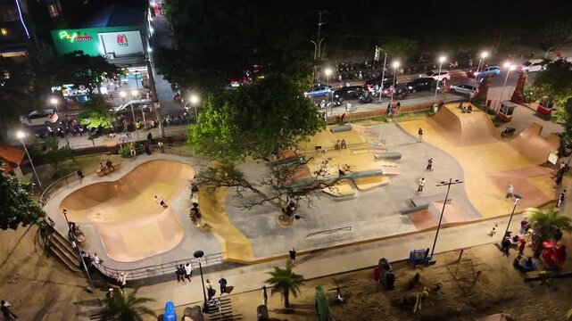 Top view on skatepark pool and professional cool skateboarder ride with flow and style. Skateboard man perform tricks, ride inside skate park in urban city area. Drone aerial shot of skateboarding