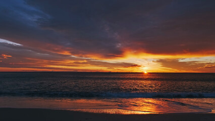 Obraz premium Sunset over sea with vibrant red and orange sky