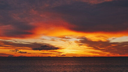 Obraz premium Sunset over sea with vibrant red and orange sky