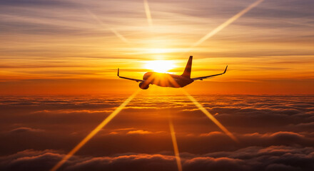 Silhouette of plane flying above dense cloud layer during sunset, representative of travel, freedom, and exploration against bright sun burst