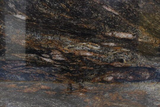 Close-up of a Titanium granite slab showing unique mineral composition with a blend of dark colors and shimmering copper accents.