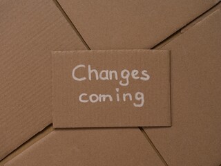 Cardboard with handwritten words Changes Coming on a cardboard pieces background.