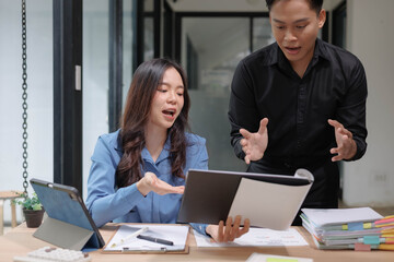 Obraz premium A woman and a man are looking at a laptop together. The woman is smiling and the man is frowning. The laptop is open to a document 