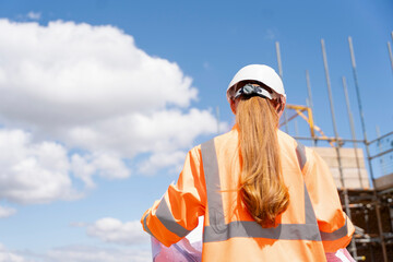 Builder woman working on construction site and using drawings to check works progress © Iryna