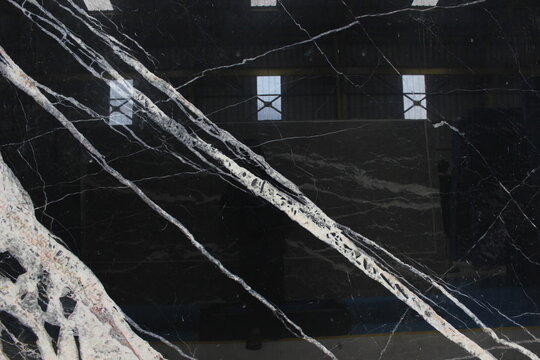 Portoro Silver black marble texture with dramatic diagonal white and silver veins on a glossy surface.