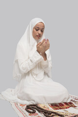 Kneeling on rug with cupped hands, bowed head and white headscarf, ornate carpet detail, calm studio ambience, reflective posture