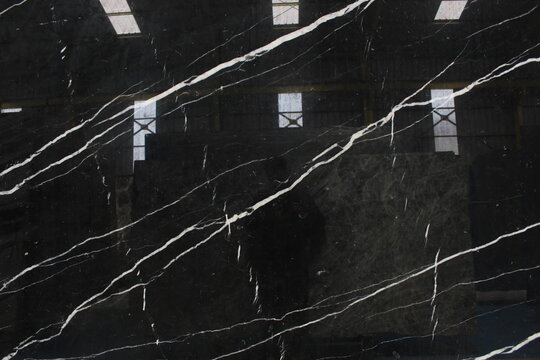 Nero Marquina marble with a solid black background and thin linear white veins crossing diagonally.