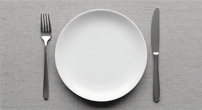 Simple minimalist overhead view of a clean white dinner plate centered between a polished stainless steel fork and knife resting on a textured gray placemat ready for dining.