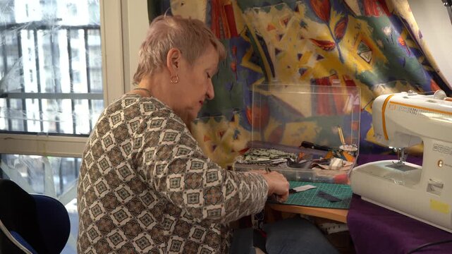 Elderly senior woman sewing. Grandmother doing needlework