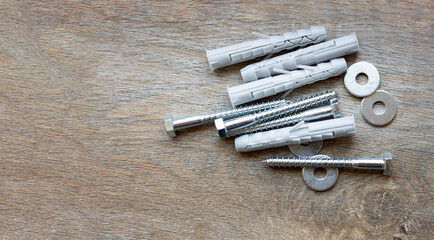 Plastic dowels and metal bolts laid out on a wooden surface, copy space. © Natalia
