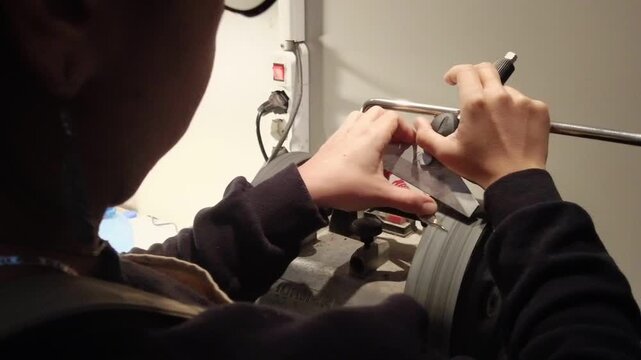 Close-up of hands sharpening a knife on a grinding wheel with precision and care