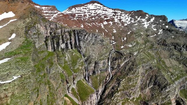 Aerial drone view of the mountain shelter Bivacco Piano della Parete in Switzerland. Surrounded by mountains and a waterfall, silence and serenity prevail. Outdoor adventure and a traveling lifestyle.