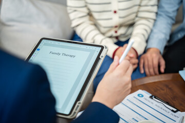 Young Asian couple or family sitting on sofa and talking with a professional therapist at home or...