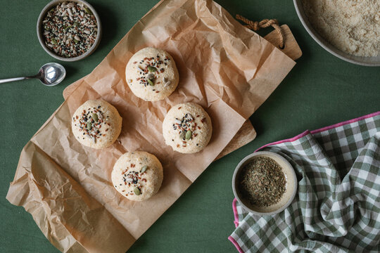 Overhead view of Low carb keto buns made with ricotta, almond and coconut flour and eggs topped with assorted seeds on a table with ingredients