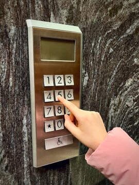 Close-up of a young woman's Hand pressing the fifth floor button in an elevator