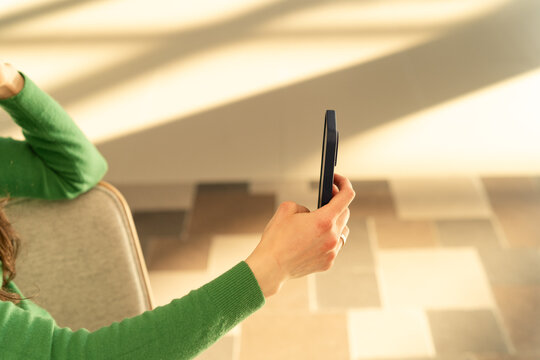 Close-up of a woman sitting on a sofa using a mobile phone