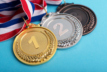 High angle view of gold, silver and bronze medals on blue background