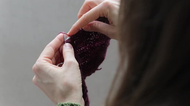 woman knits wool clothes on knitting needles. skills of making clothes from yarn, hobbies meditation. woman knits soft purple sweater at home. mental health, develop fine motor skills hands. handmade.