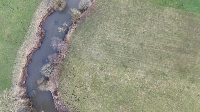 Aerial Drone Flight Along a Winding River Through Rural Farmland