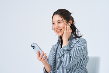 イヤホンを装着してスマートフォンを手にする若い女性