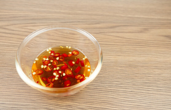 Red chili peppers fish sauce glass bowl on wood background.
Dipping Prik Nam Pla traditional thai restaurant.
top view