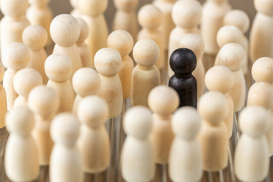 A single black figure among white ones. Social concept. Black sheep, a person who stands out in a crowd, doesn't fit in with the rest. pushed out of the social circle.