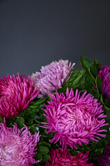 Obraz premium A bouquet of bright Aster flowers on a dark background.