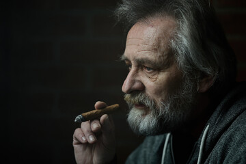 Senior bearded man smoking on balcony classic big cigar in detail