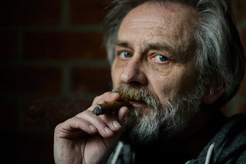 Senior bearded man smoking on balcony classic big cigar in detail