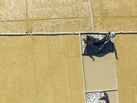 Aerial view of a person working on a rooftop, the contrasting textures of the raw materials and the finished sections under the sun, Cox's Bazar, Chittagong Division, Bangladesh.