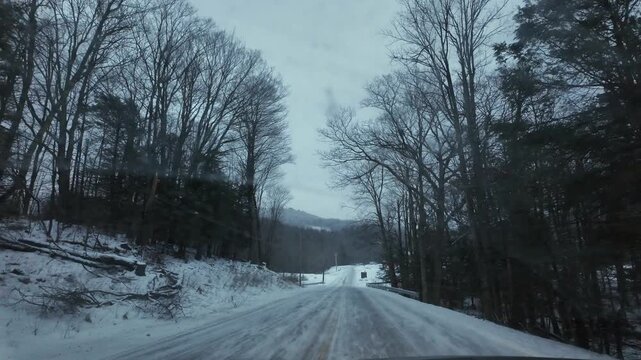 Driver's POV on an icy snow-covered rural road during blue hour in winter