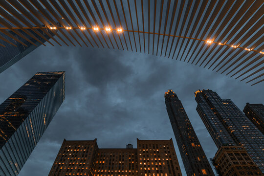 View of towering skyscrapers piercing the dusky sky, framed by the warm glow of overhead lights, creating a captivating urban scene, New York City, USA.