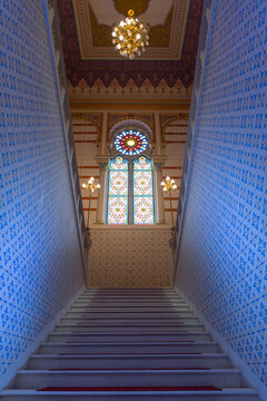 View of a staircase with intricate blue patterns on the walls leading to a stained glass window and ornate ceiling, Sarajevo, Federacija Bosne i Hercegovine, Bosnia and Herzegovina.